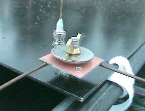 A close-up view of one corner of the antenna plate, showing the base of one of the four verticals and a pair of the radials.